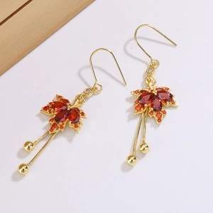 Elegant gold-tone maple leaf earrings with red crystals and delicate tassel drops