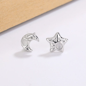 Close-up of star and moon silver earrings with hammered texture and opal-like stones