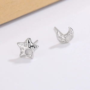 Detail of silver star and moon earrings with lava texture and opal-like stones