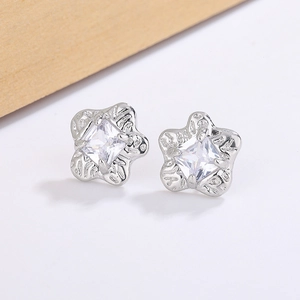 Macro shot of silver star stud earrings with square zircon and wave textured finish
