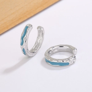 Detail of silver irregular texture ear cuffs with vibrant blue enamel finish