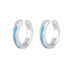 Detailed close-up of silver ear cuffs with blue enamel and irregular liquid metal texture
