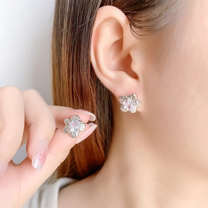 Elegant silver flower stud earrings with square zircon stone worn on a female model