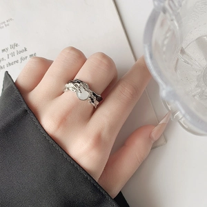 Irregular lava texture open ring with white heart detail on hand in a moody setting