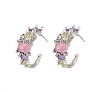 Detailed close-up of C-shaped silver earrings set with colorful cubic zirconia