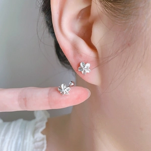 Macro detail of silver flower stud earrings showing brushed metal texture and ball screw backs