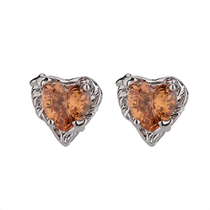 Detailed close-up of heart-shaped earrings with amber resin and vintage engraved metal