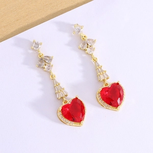 Detail of elegant gold drop earrings featuring red heart-shaped stones and clear zircons