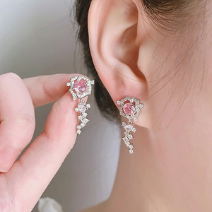 Dettaglio di orecchini in argento con zircone rosa e nappe di cristallo