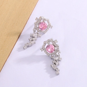 Dettaglio macro di orecchini con zircone rosa, cornice esagonale d'argento e pendente