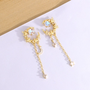 Close-up of golden moon and bird tassel earrings with blue stones and fine diamonds