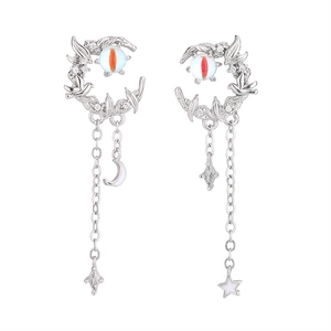 Close-up of asymmetric silver moon earrings with tassels, birds, and cat-eye stones