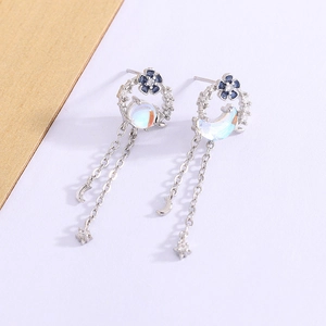 Detailed macro view of silver moon and flower earrings with zircon and blue moonstone effect