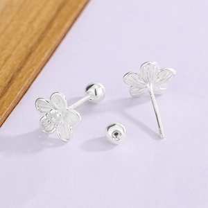 Detail of silver S925 stamped screw-back earrings with hollow floral design