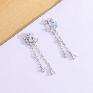 Detailed shot of long silver butterfly moon earrings with opal stones and star tassels