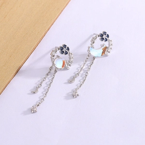 Detail of asymmetric silver floral earrings with blue star and moon tassels
