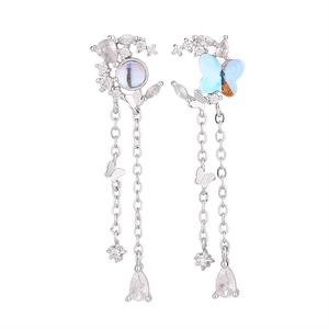 Detail view of asymmetric moon and butterfly tassel earrings with blue moonstones