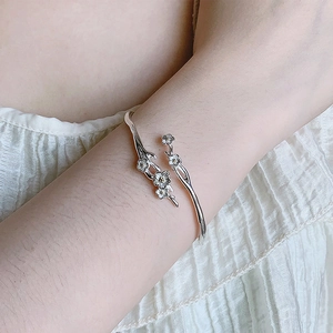 Close-up of adjustable jasmine flower bracelet on wrist with silver floral texture