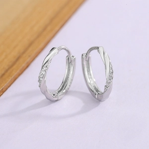 Macro shot of twisted silver-tone earrings with white cubic zirconia inlay detail