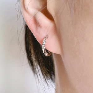 Silver twisted hoop earrings with micro-inlaid zircon stones worn by a model