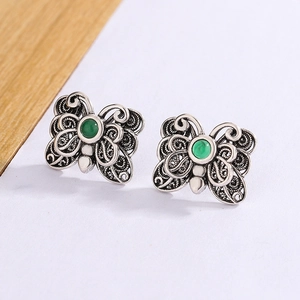 Close-up of vintage silver butterfly earrings with hollow wings and green agate inlay
