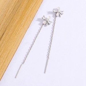 Gros plan détaillé de boucles d'oreilles papillon avec pompons argentés et pierres blanches