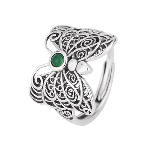 Macro detail of retro butterfly ring featuring green stone and hollow filigree design