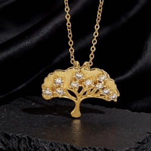 Dettaglio macro del ciondolo albero della vita dorato con cristalli su seta nera