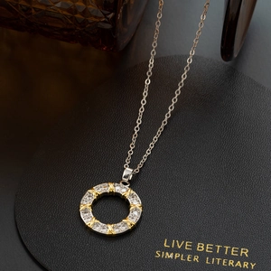 Silver round zircon necklace with gold cross accents on black leather jewelry display