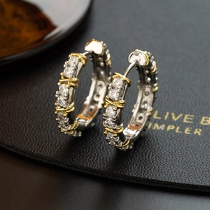 Two-tone gold and silver hoop earrings with cubic zirconia on black leather stand