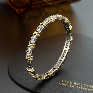Close-up of gold and silver bangle with sparkling zircons and X-shaped cross details