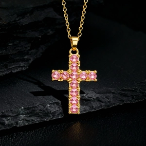 Détail d'un collier pendentif croix plaqué or avec des pierres de zircon rose brillant