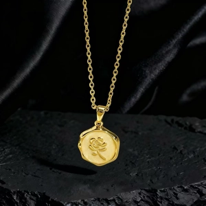 Detalle de colgante de moneda de oro con relieve de rosa en cadena cruzada clásica