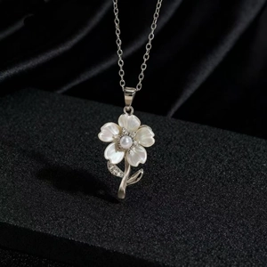 Detalle del collar de flores con pétalos de nácar blanco y una pequeña perla en el centro
