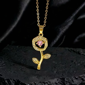 Detalle de un collar de girasol dorado con gema rosa y circonitas blancas sobre roca negra