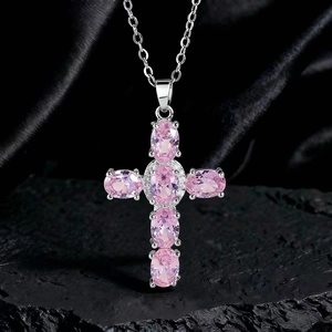 Dettaglio macro del ciondolo a croce con cristalli rosa ovali e diamanti bianchi su pietra