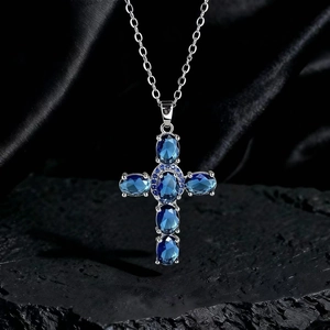Dettaglio macro del ciondolo a croce con pietre blu su espositore in roccia di lusso