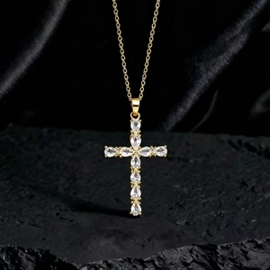 Dettaglio della collana con pendente a croce e zirconi a forma di pera su tessuto nero
