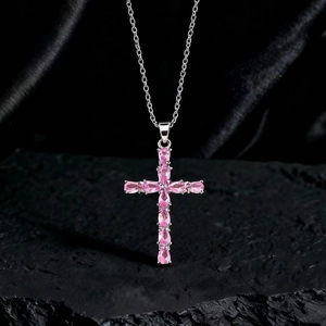Dettaglio del ciondolo a croce con pietre preziose rosa a goccia su una catena d'argento fine