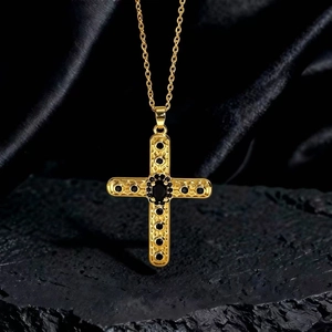 Dettaglio della collana vintage a croce d'oro con pietre nere su roccia scura