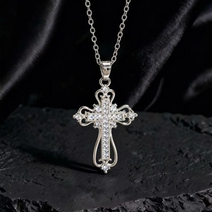 Dettaglio di un ciondolo a croce in argento vintage con zirconi su seta nera