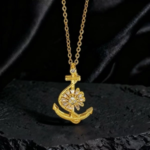 Detalle del colgante de ancla bañado en oro con circonitas sobre base de piedra negra
