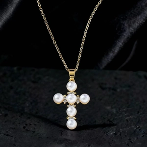 Vista macro dettagliata di una collana con ciondolo a croce dorata con perle e zirconi
