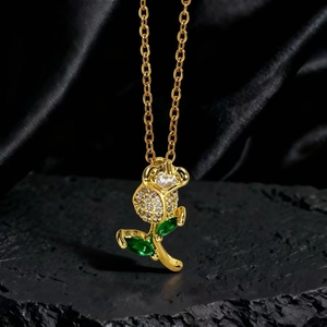 Detalle del colgante de rosa dorada con capullo de circonita brillante y hojas verdes