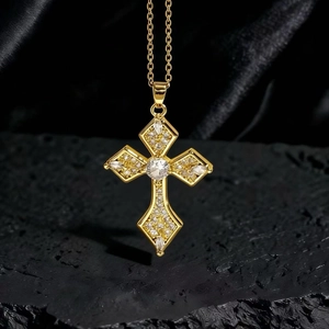 Dettaglio di una collana con ciondolo a croce dorata e gemme bianche su fondo nero
