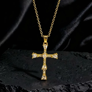 Dettaglio di una collana con ciondolo a croce dorata e zirconi su velluto nero