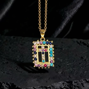 Dettaglio della collana dorata con pendente a croce in zirconi colorati su pietra nera