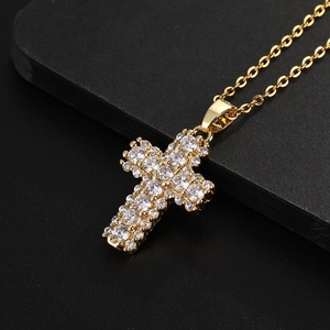 Dettaglio della collana con croce dorata e zirconi bianchi su una scatola nera elegante