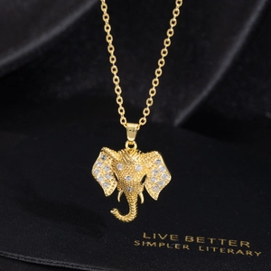 Detailed view of a gold elephant pendant with micro-set cubic zirconia on black silk background