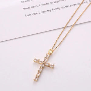 Gold plated cross necklace with pear-shaped colorful zircon pendants on beige background